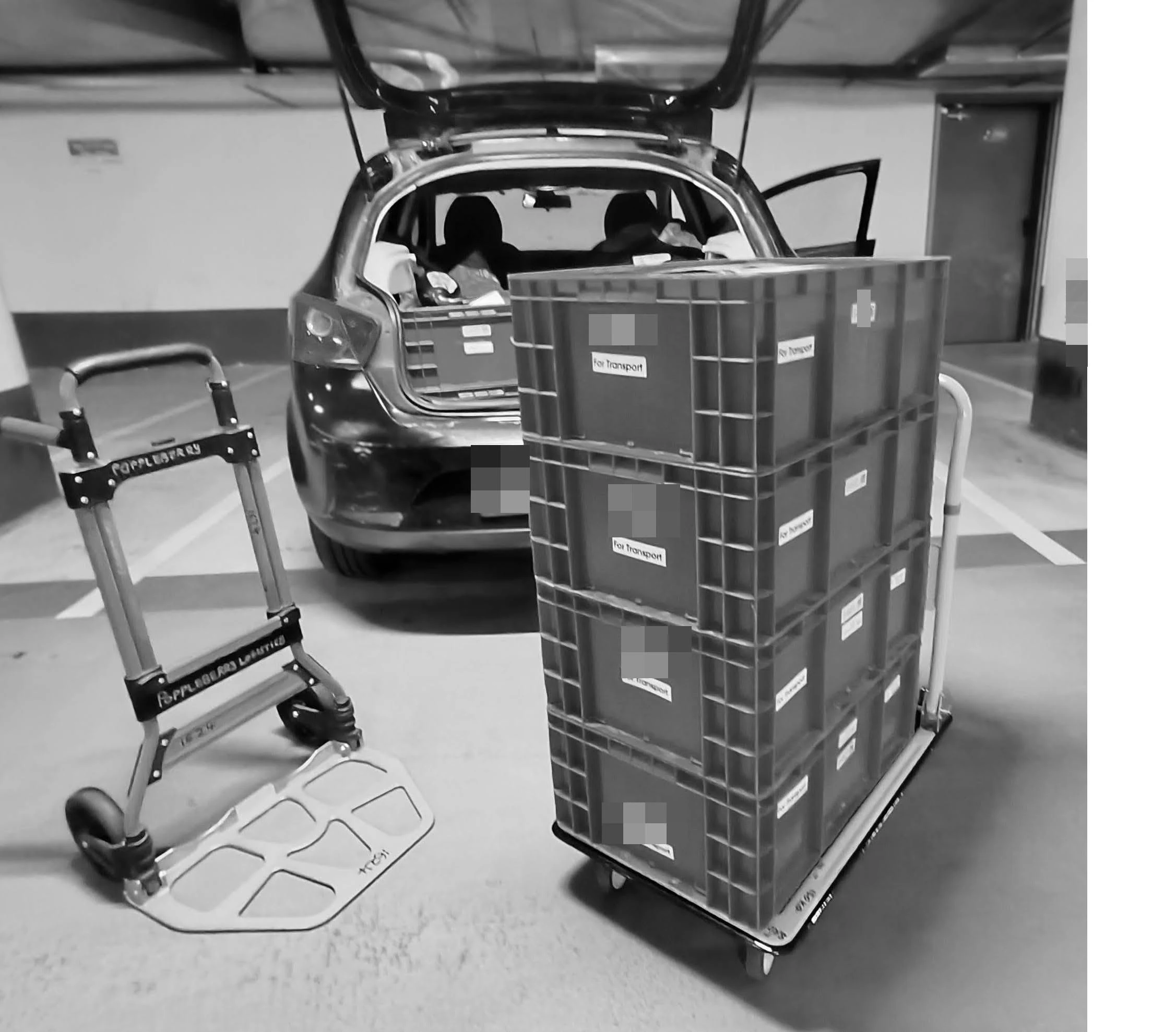 The whole moving kit in one frame: car, folding hand truck, a column of boxes.