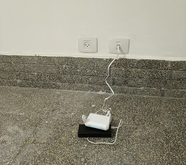 Photo of the GL.iNet router on power bank deployed at shelter stairs, connected to wall power