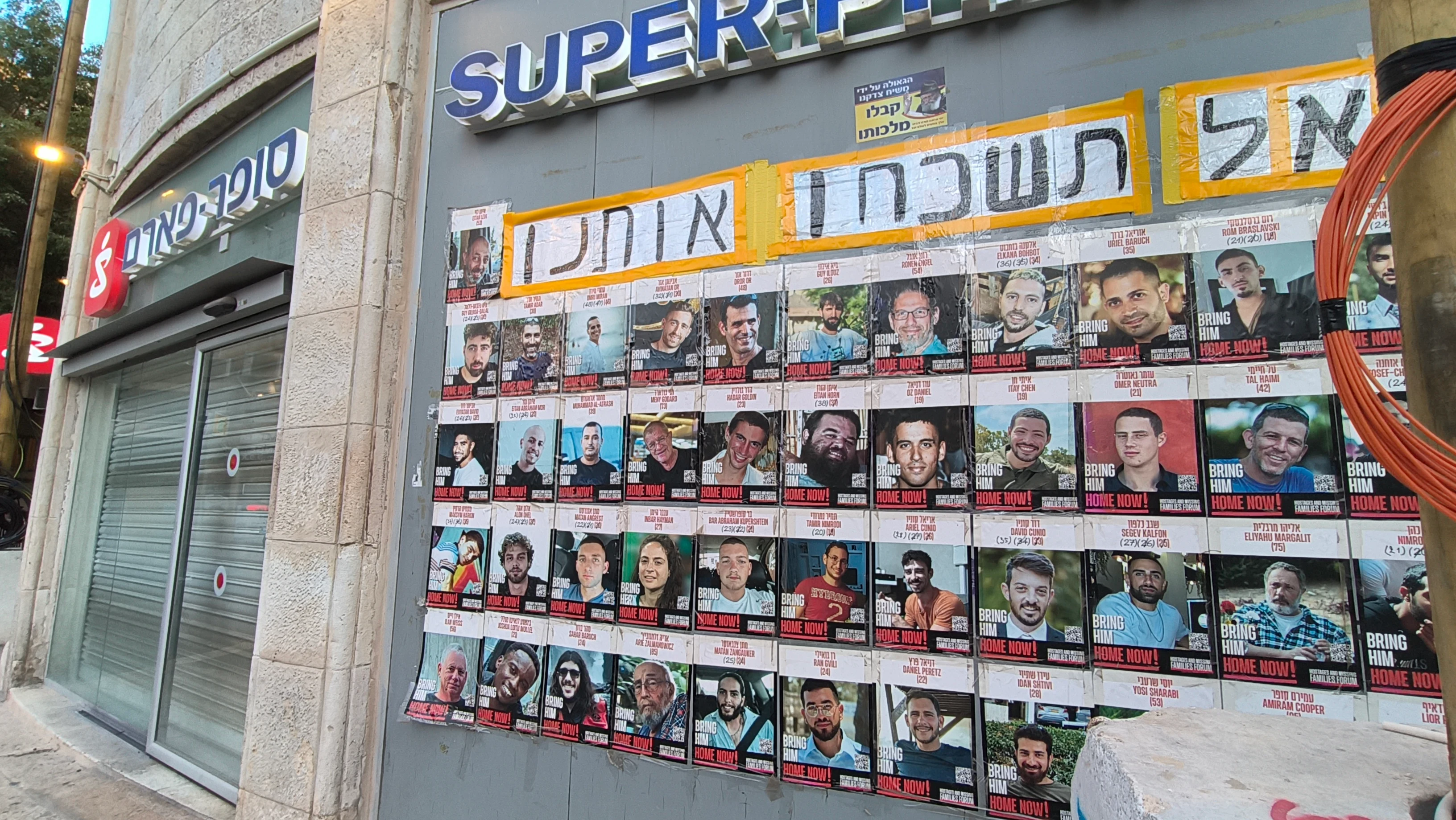 A hostage poster outside a branch of the Israeli pharmacy chain Super Pharm. The Hebrew above the individual posters reads 