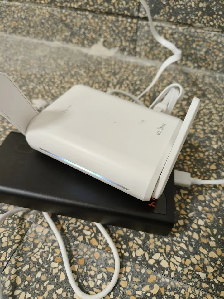 Closeup photo of GL.iNet router on power bank with ethernet cable connected, deployed in shelter stairwell