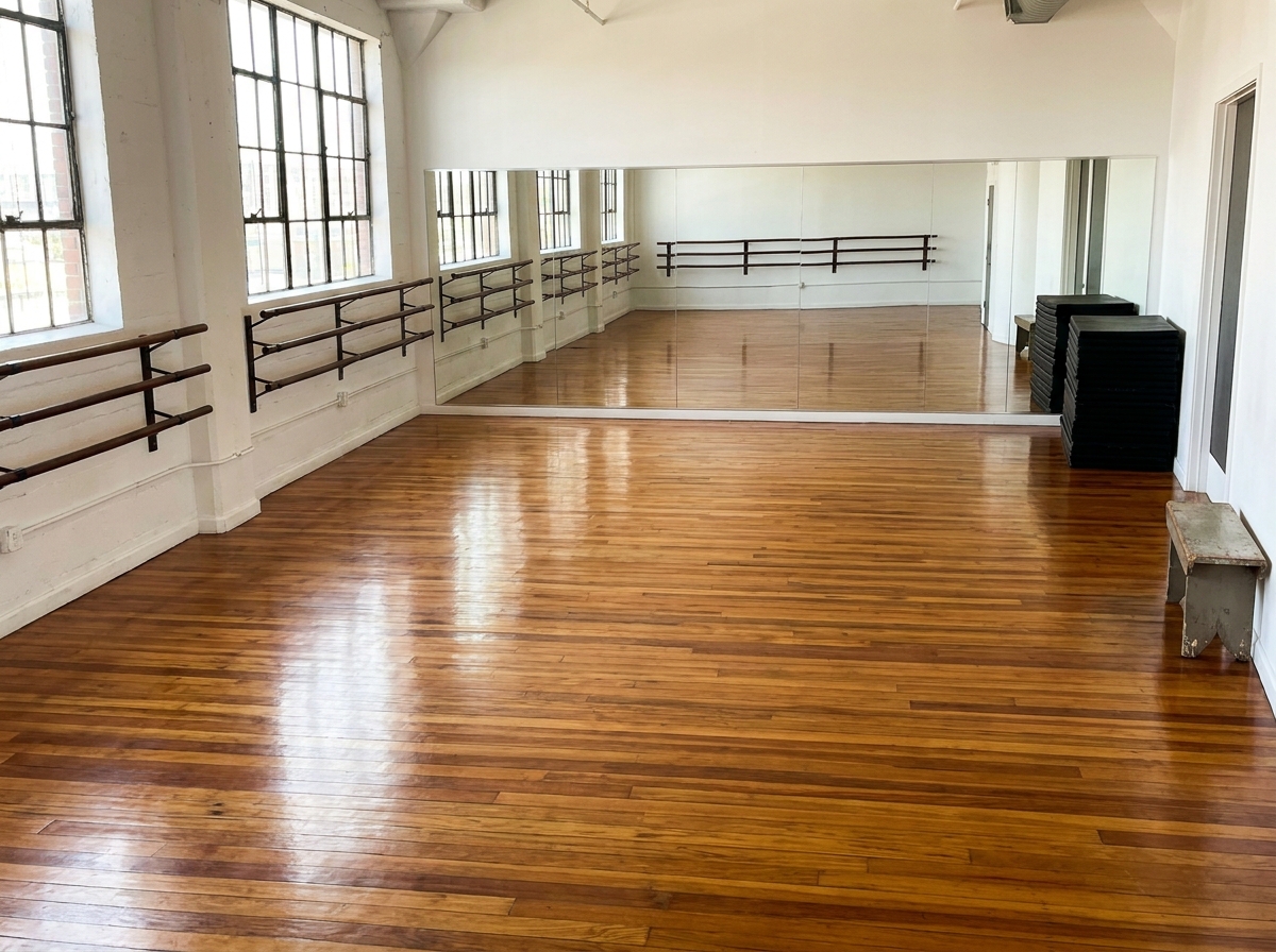 An empty dance studio with mirrors and barres, ready for a dance class.