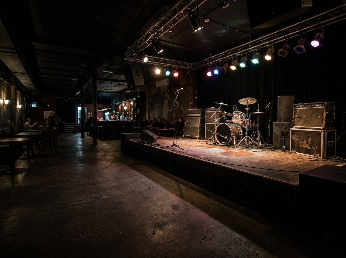 An empty stage at a rock club, set up with instruments and ready for a show.