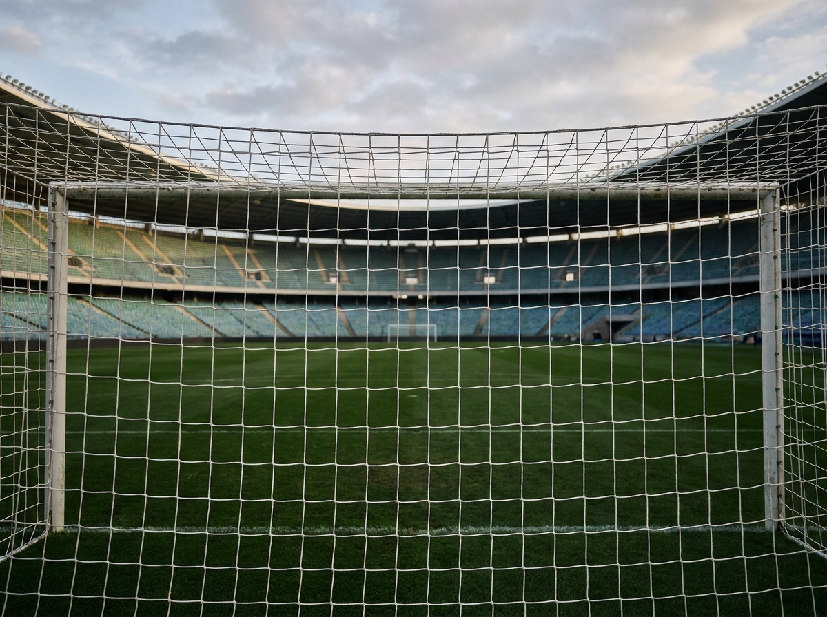 View of an empty soccer stadium through the goal net.
