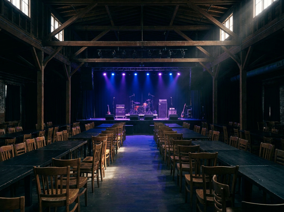 An empty music hall with a lit stage, set up for a cover band performance.
