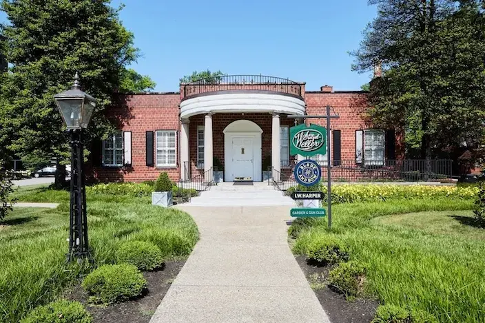 The entrance to the Stitzel-Weller Distillery, featuring a red brick building with white columns and a central white door.