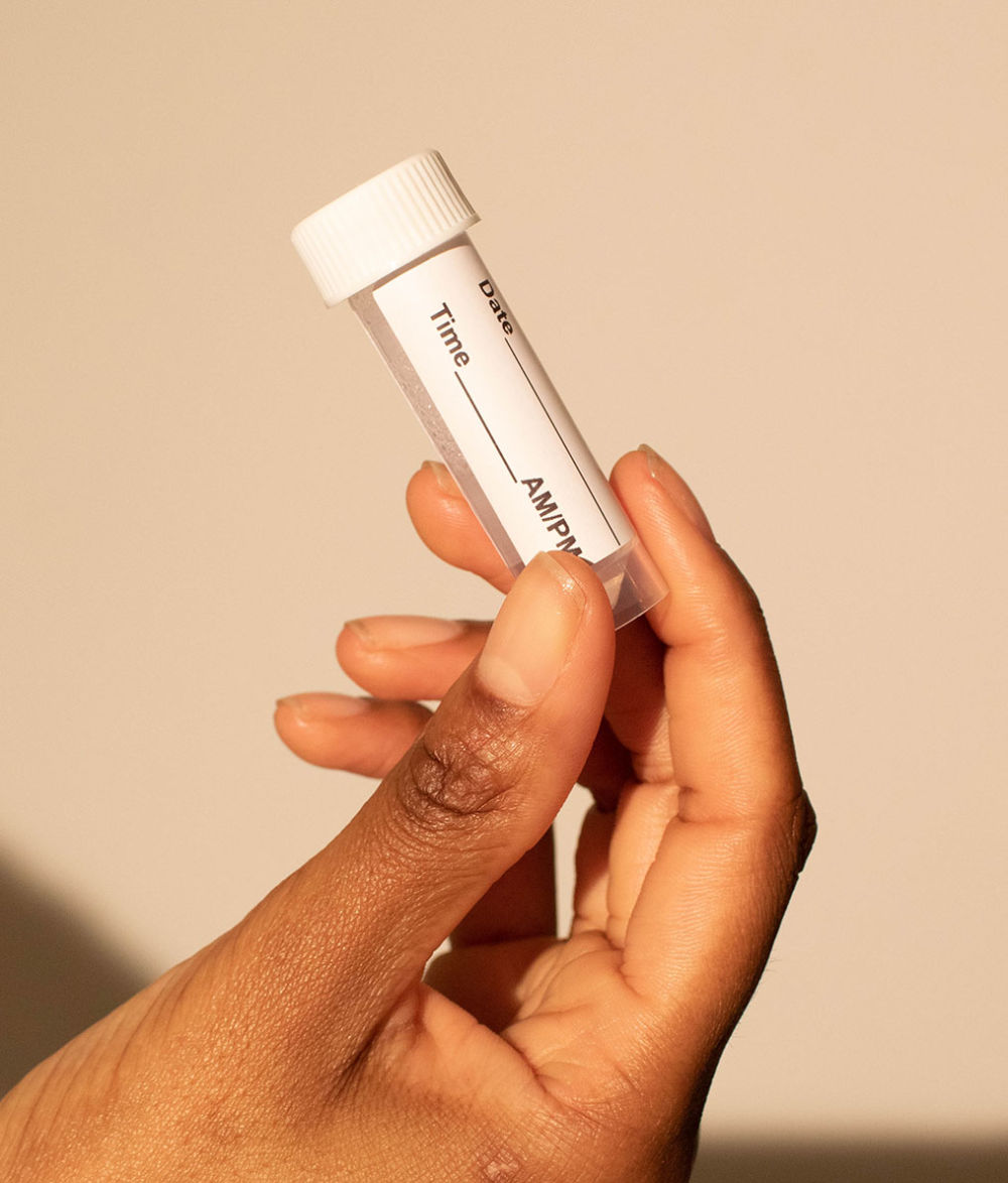 Hand holding the saliva collection tube with label