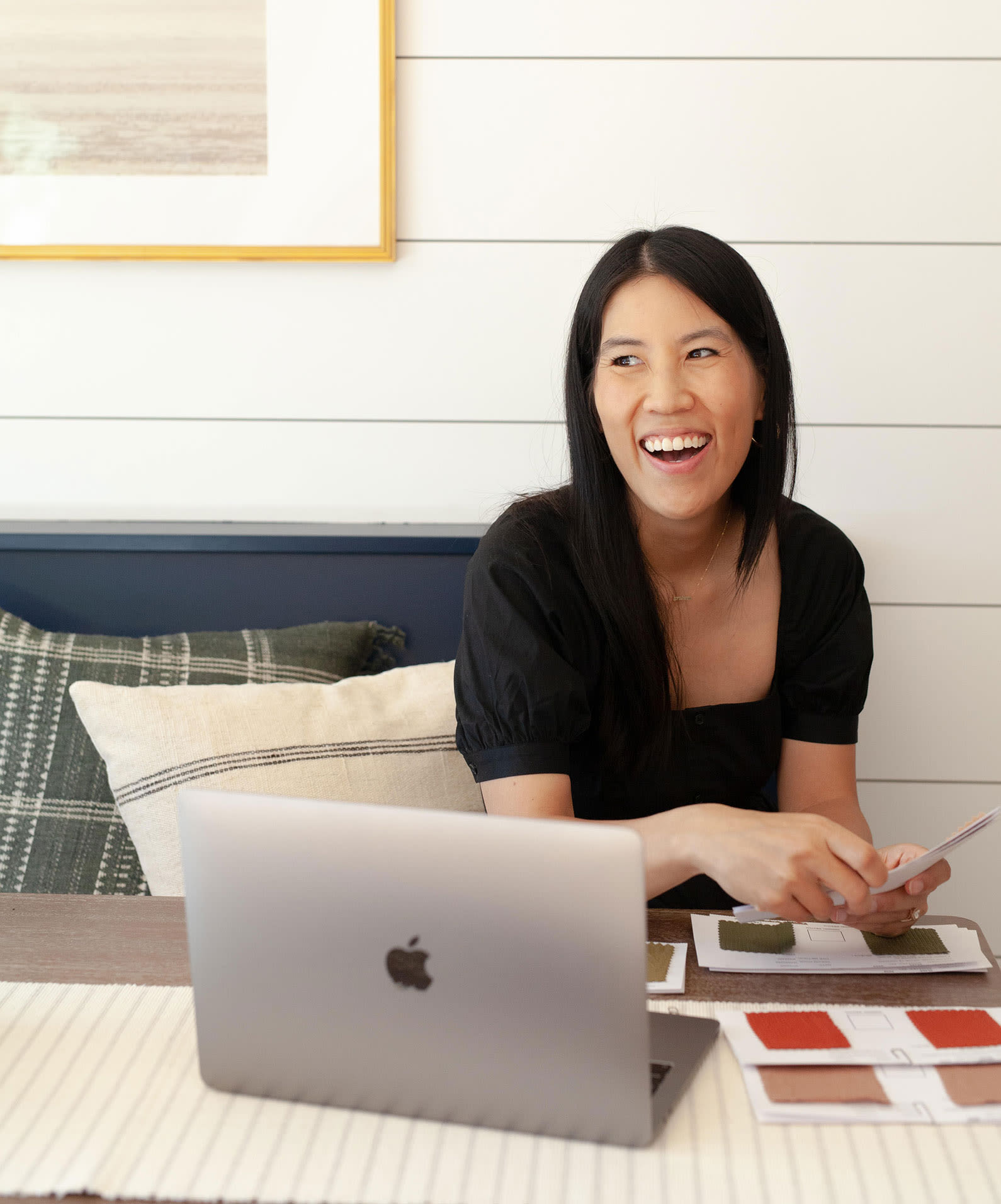 Justine Liu at her desk with a laptop and fabric swatches.