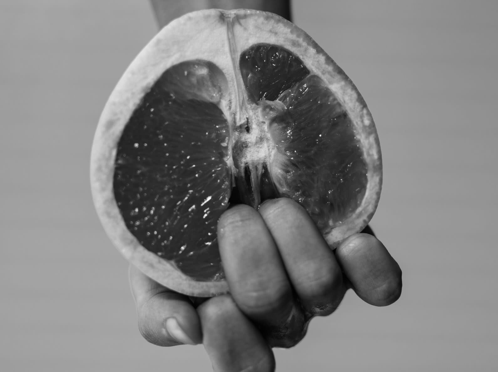 Sliced grapefruit with hand and fingers