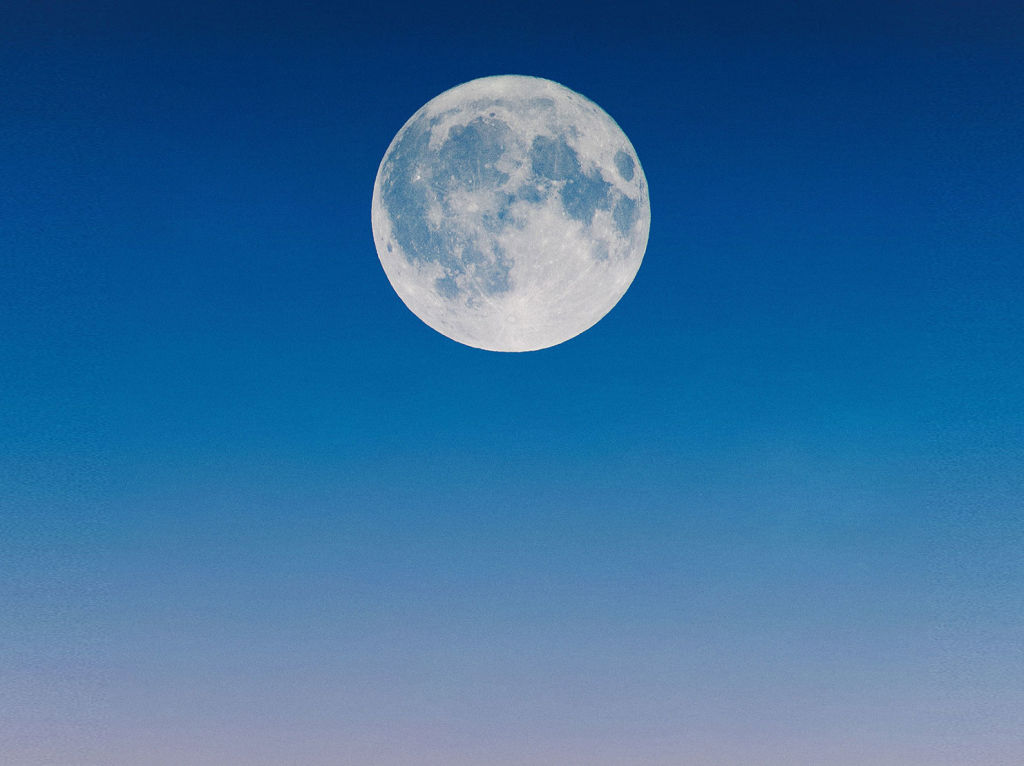 Moon rising in a pink and blue gradient sky