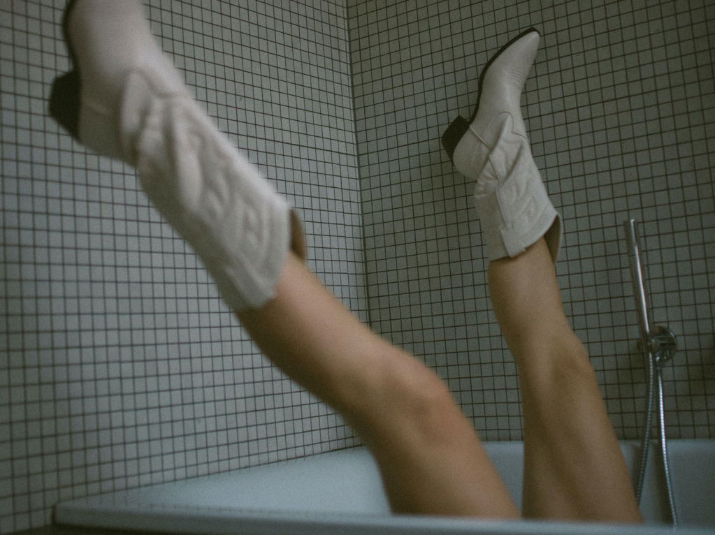 woman in bathtub with white cowboy boots