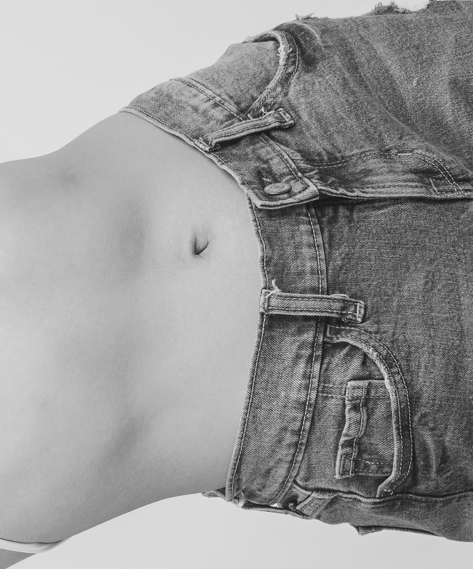Woman's bare stomach and waist of jeans.