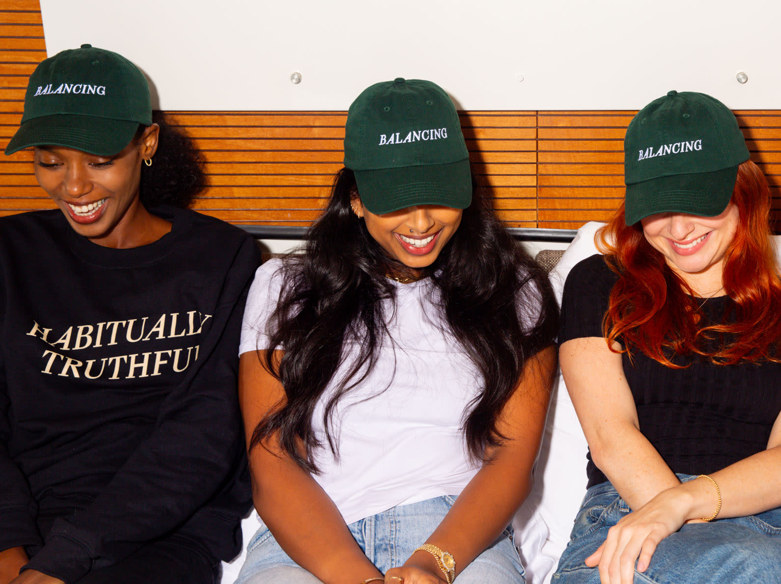 Four women wearing hats embroidered with 'Balancing'