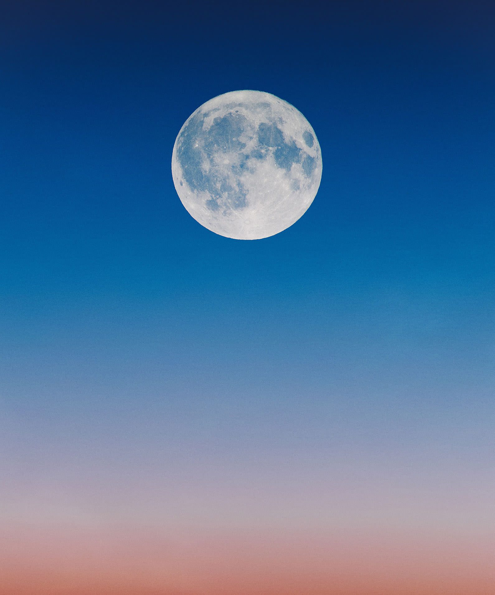 Full moon in a light blue and pink sky