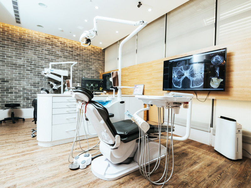 Modern empty dentist's office with state-of-the-art equipment and TV screens and subway tiled walls.