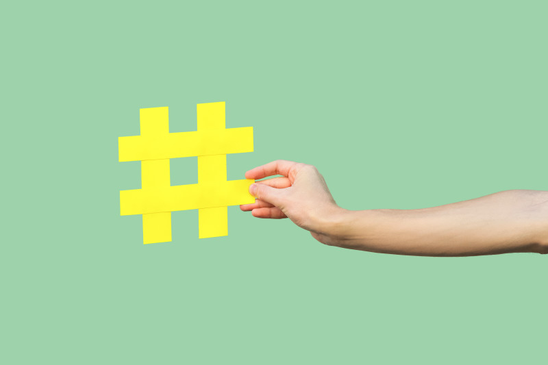 Close-up of hand holding large yellow hashtag sign