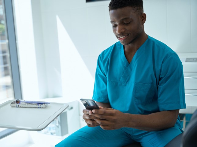 man in scrubs reading best dental blogs on his phone