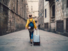 woman in yellow coat with luggage taking a career break