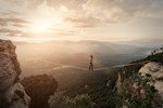 Man walking tightrope across ravine at dawn