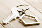 Sterling silver keychain of the outline of a house sitting on a wooden table.