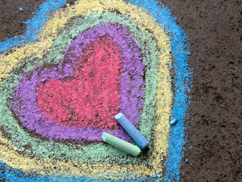 Heart drawn in colorful chalk on asphalt
