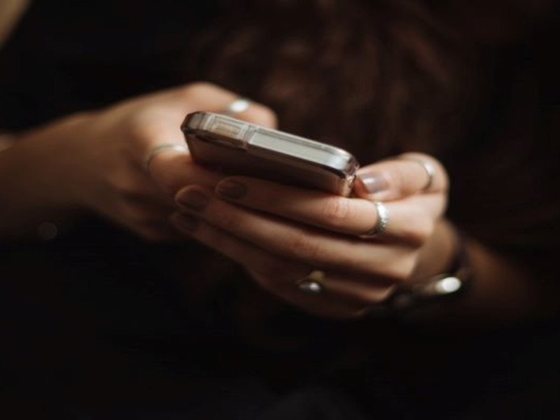 Pair of female hands with rings texting on a smartphone