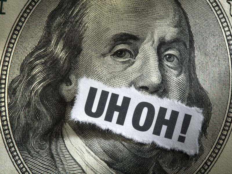 Close-up of Benjamin Franklin's face on $100 bill with the words "uh oh!" written over his mouth.