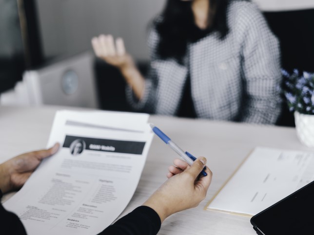 interviewer looking at business womans resume not asking illegal interview questions