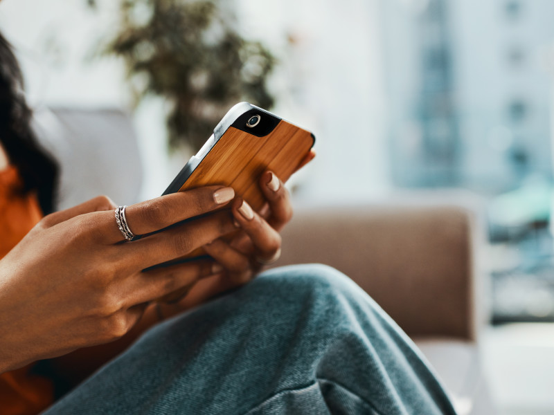 Woman in an orange blouse using an app on her smartphone.