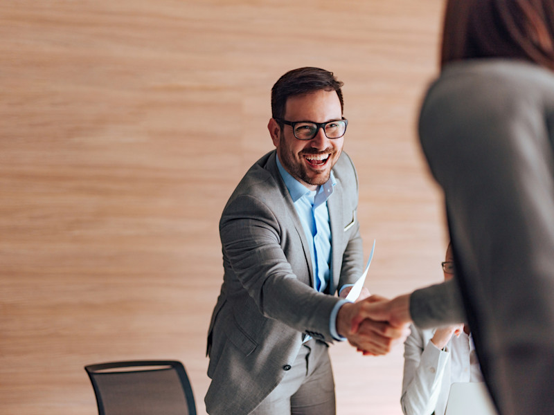 Cheerful male job candidate shaking hands with female interviewer.