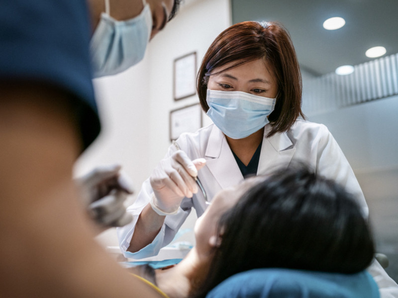 亚洲女牙医用灯照射病人
