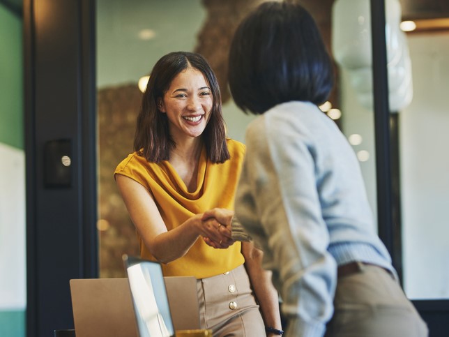 woman smiling shaking other woman's hand | insurance claims team must-haves