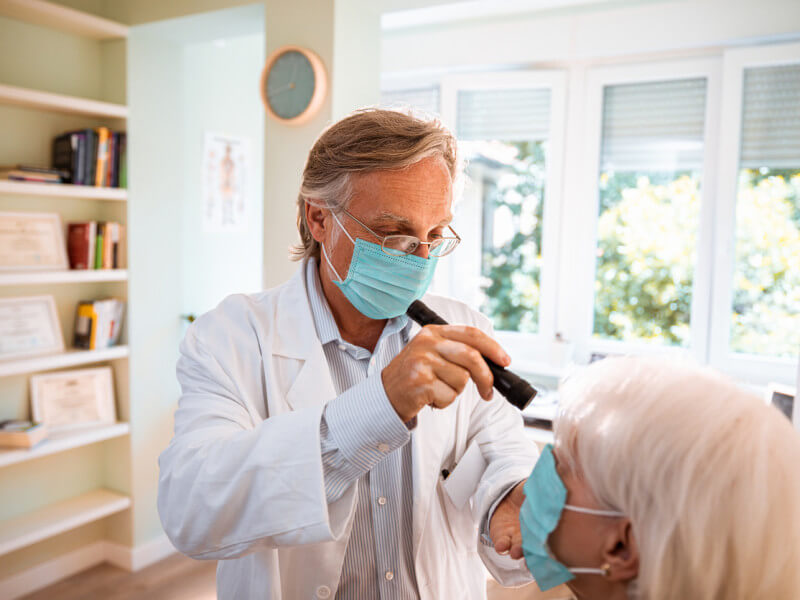 optometrist in mask giving patient an eye exam