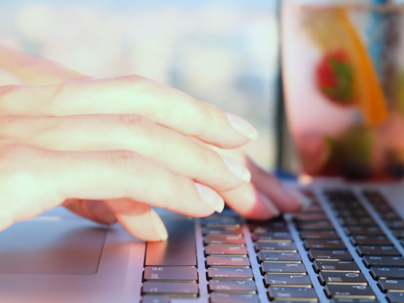 Woman's hands typing on a keyboard outdoors