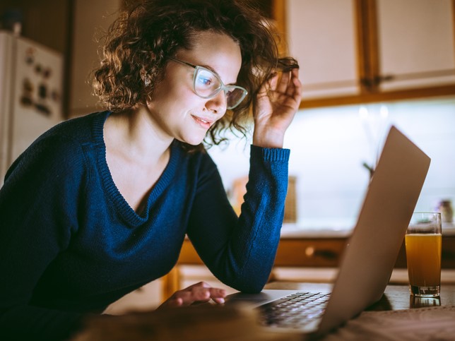 woman smiling at laptop in dark room debunking medical malpractice insurance myths