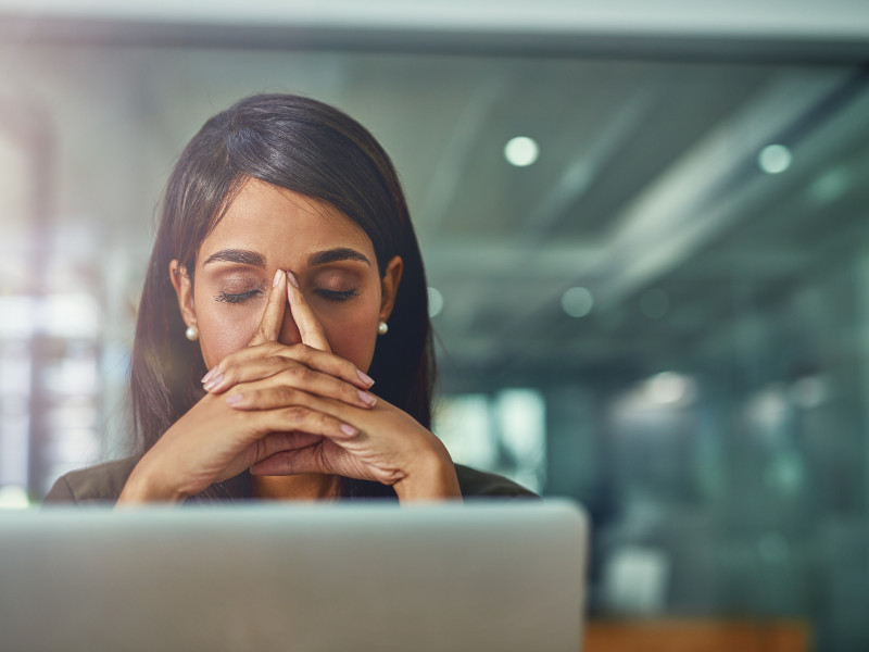 Shot of a young businesswoman looking stressed out while working in an office