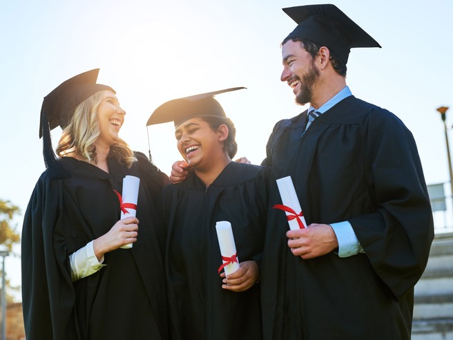 three graduates in caps and gowns looking up nursing scholarships and grants