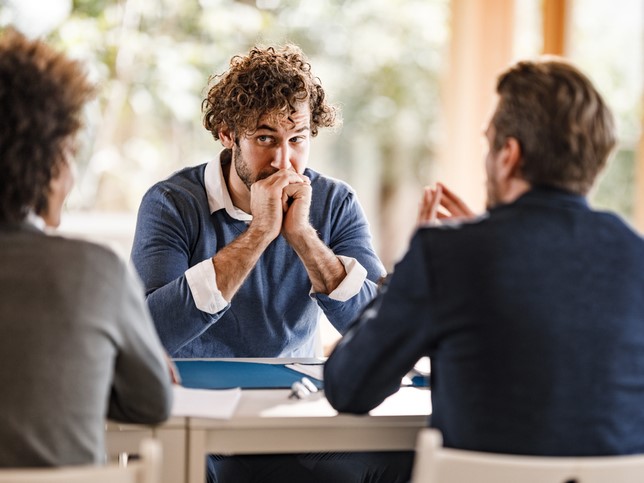 man sitting in front of panel while displaying red flags during an interview