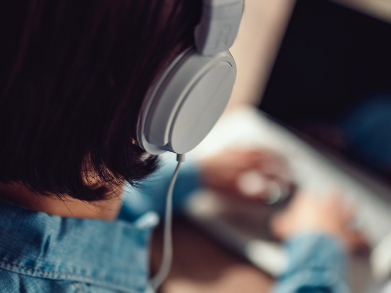 Woman with Beats headphones listening to podcasts while on laptop.