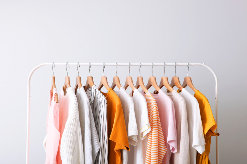 A clothing rack holding a variety of women's blouses in different shades of white, yellow, and pink.