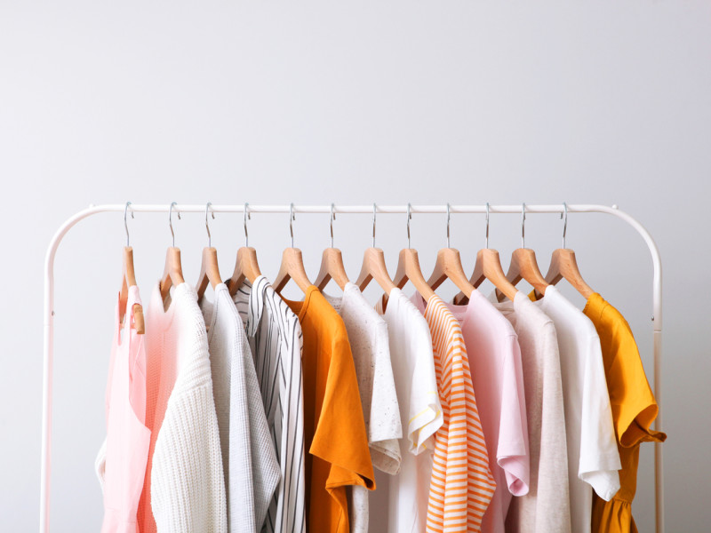 A clothing rack holding a variety of women's blouses in different shades of white, yellow, and pink.