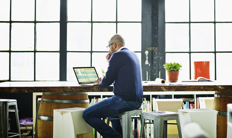 Man sitting at desk with laptop doing data analysis 470x280