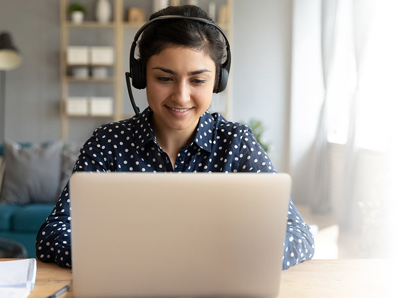 Woman with headphones working at home on laptop