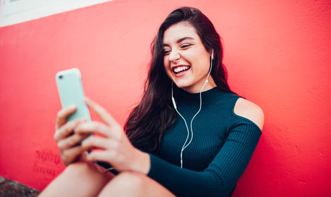 smiling woman listening to music with mobile phone