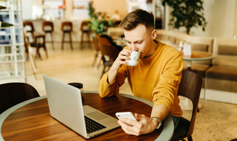 man drinking coffee working on laptop and mobile 470x280