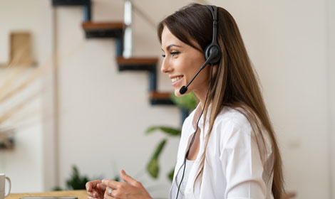 happy customer service agent with headphones looking at laptop