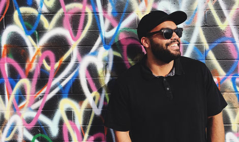 man smiling in front of graffiti wall art