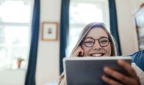 Woman smiling using tablet at home 470x280