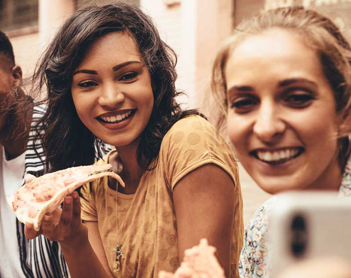 People eating pizza taking selfie