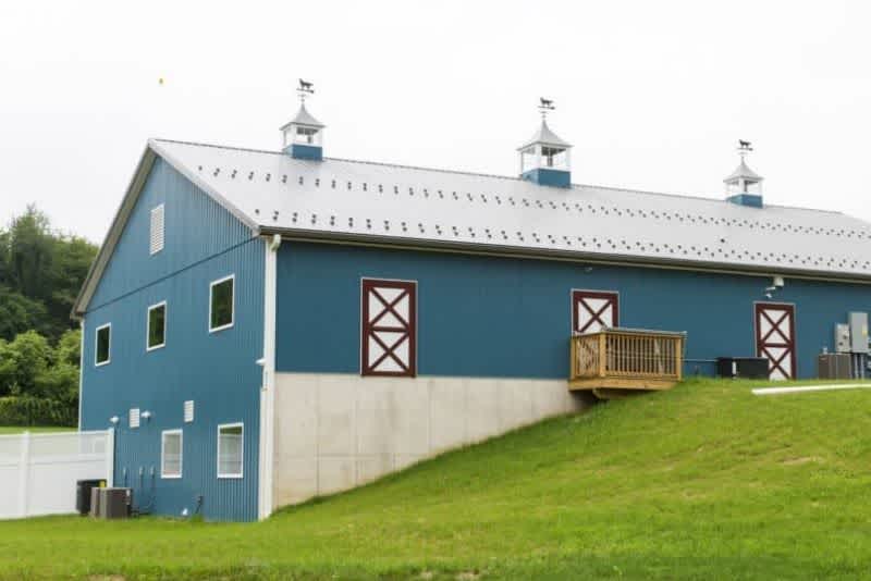 a blue bank barn on a small green hill