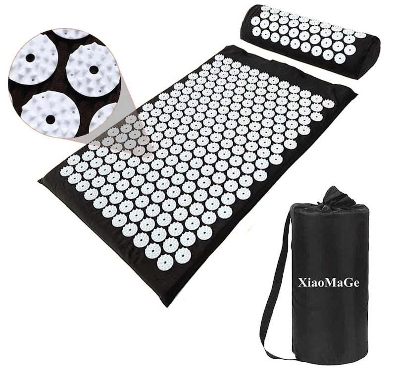 A black and white acupressure mat and pillow set with the traveling bag next to it